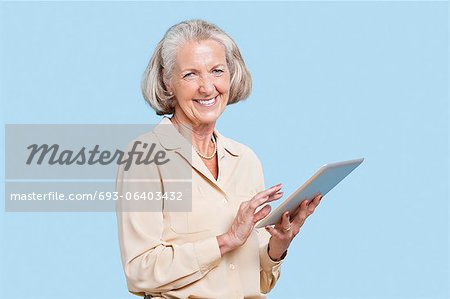 Portrait of senior woman using tablet PC against blue background