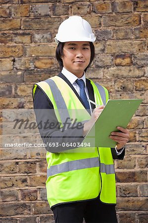 Portrait of young supervisor holding clipboard at construction site