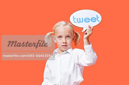 Portrait of a young girl holding tweet bubble against orange background