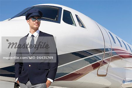 Handsome young pilot standing by private airplane