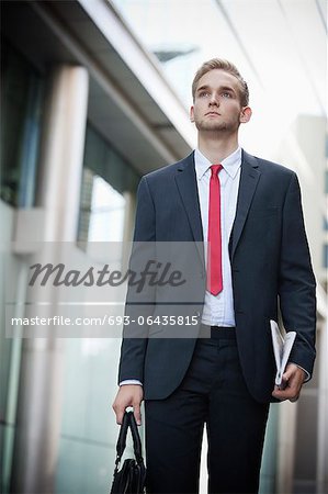 Young businessman in suit holding newspaper and bag