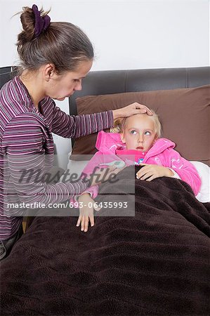 Mother checking unwell girl's temperature at home