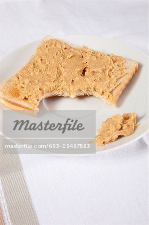 Peanut butter on slice of bitten bread