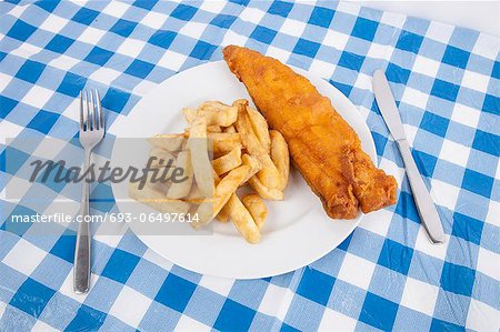 Close-up of fries and meat with fork and table knife on table