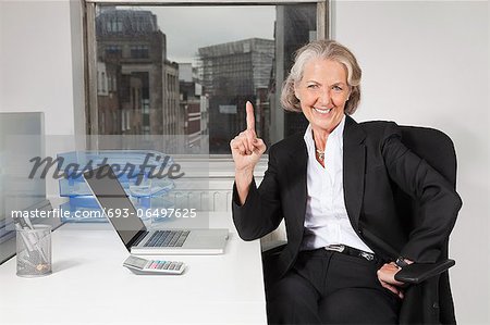 Portrait of senior businesswoman with laptop at desk in office