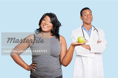 https://image1.masterfile.com/getImage/693-06497723em-overweight-mixed-race-woman-holding-green-apple-with-doctor-over-blue.jpg