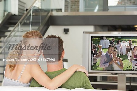 Portrait of young Caucasian woman with man watching movie on television in living room