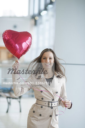 Businesswoman holding heart shaped balloon and smiling