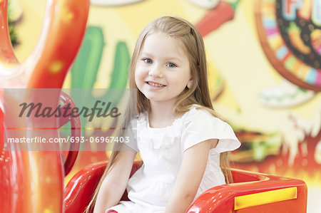 Young girl sitting on childrens car ride
