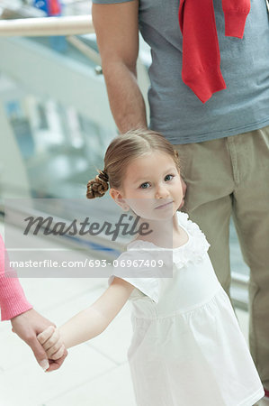 Close-up of young girl holding parents hands