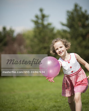 Young girl playing with purple ball in the park