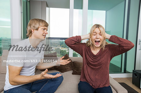 Man trying to talk as woman yells out aloud in living room at home Man trying to talk as woman yells out aloud in living room at home
