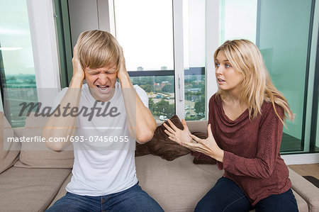 Woman trying to talk as man yells out aloud in living room at home Woman trying to talk as man yells out aloud in living room at home