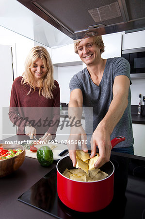 Happy man cooking pasta with woman in kitchen