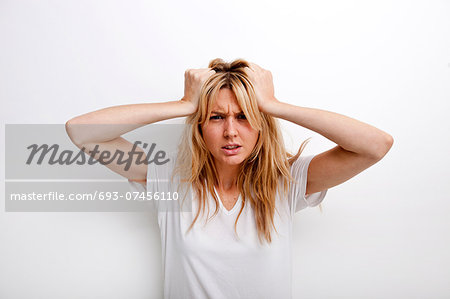 Portrait of frustrated woman pulling against white background Portrait of frustrated woman pulling against white background