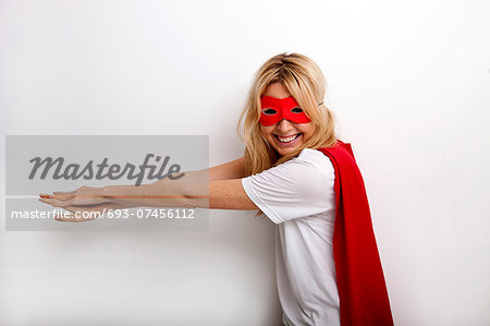 Side view portrait of happy woman in superhero costume against white background