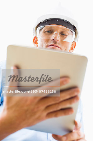 Low angle view of male architect using tablet PC against sky