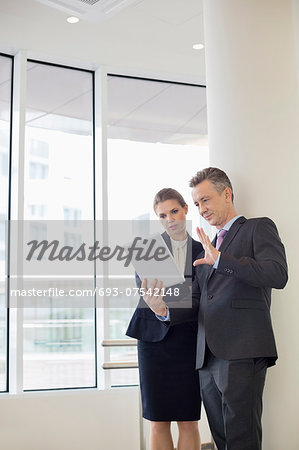 Businessman using digital tablet with female colleague in office