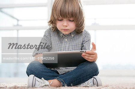 Full length of boy using digital tablet in living room
