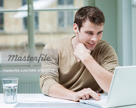 Young businessman using laptop at desk in office