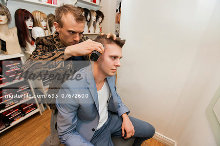 Barber shaving male customer's hair in shop