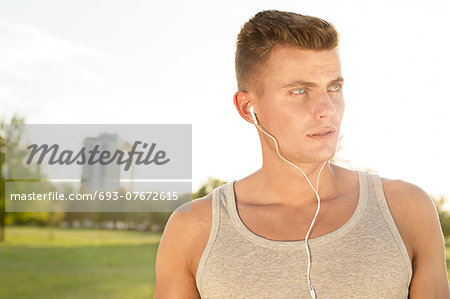 Male jogger looking away while listening music in park