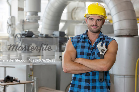 Portrait of young worker standing arms crossed in industry