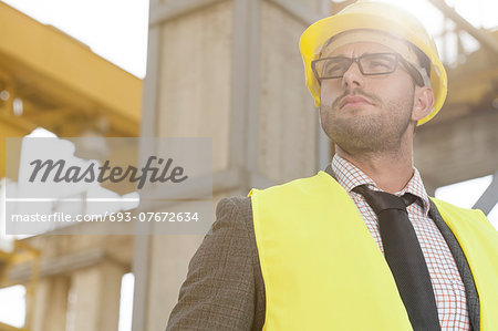 Thoughtful young male architect in protective wear at construction site