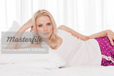 Portrait of beautiful young woman lying in hotel room