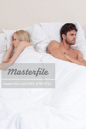 Angry young couple avoiding each other in bed Angry young couple avoiding each other in bed