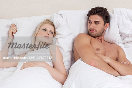 Angry young couple looking at each other in bed Angry young couple looking at each other in bed