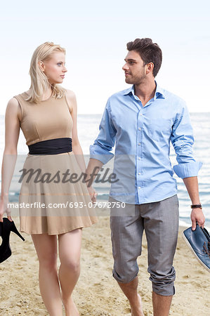 Romantic young couple holding hands and walking on beach