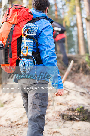 Rear view of male hiker with backpack standing in forest Rear view of male hiker with backpack standing in forest