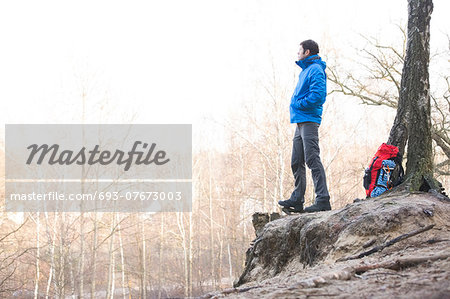Side view of hiker standing on edge of cliff in forest