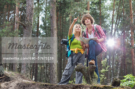Young hiking couple with map discussing over direction in forest