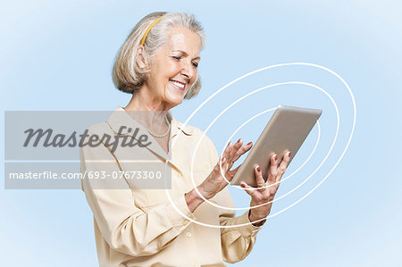 Happy senior businesswoman using tablet PC against clear blue sky