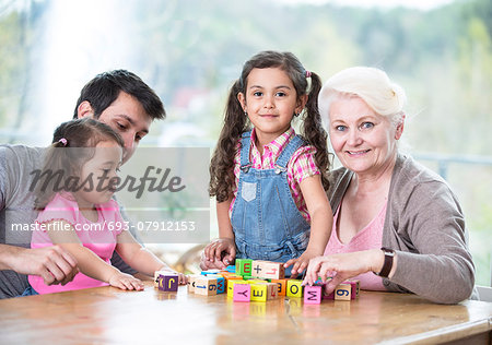 Happy three generation family playing with alphabet blocks at home