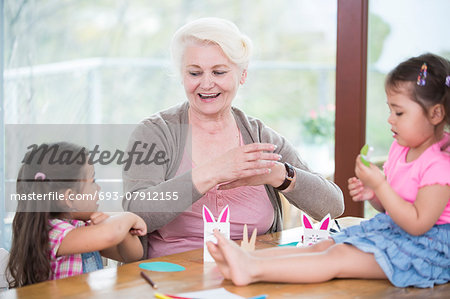 Senior woman assisting granddaughters in art work at home