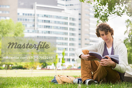 Full length of young man reading book on college campus