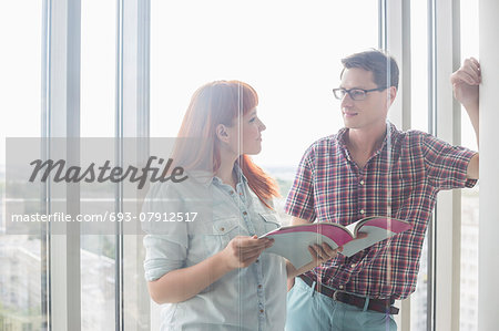 Business colleagues discussing over file in creative office