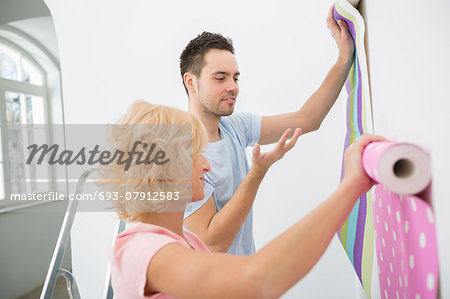 Couple holding up wallpaper samples in new house