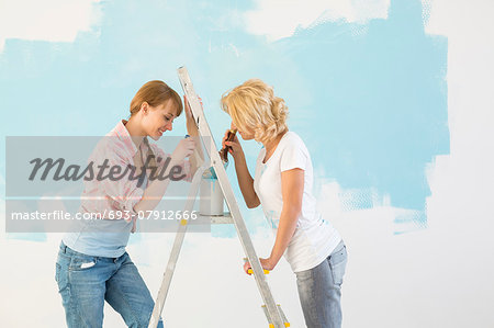 Side view of female friends painting together in new home