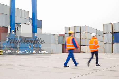 Full-length rear view of workers walking in shipping yard