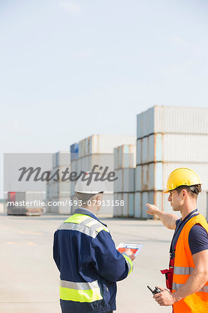 Rear view of male workers discussing in shipping yard