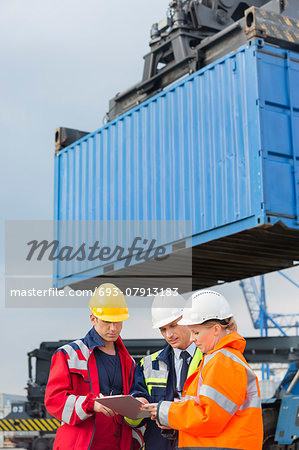 Workers discussing over clipboard in shipping yard