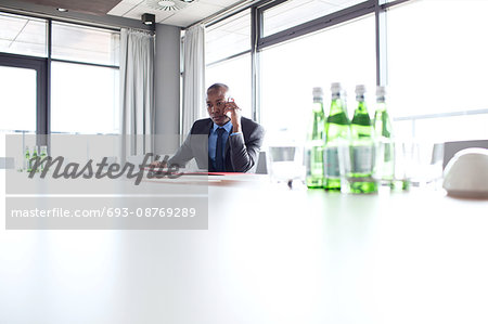 Young businessman using mobile phone at conference table