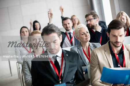 Thoughtful businesswoman sitting with colleagues in seminar hall