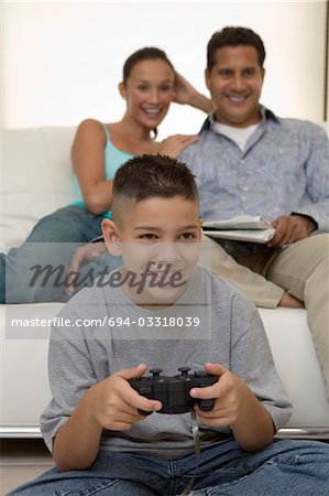 Parents Watching Son Play Video Games in living room, front view