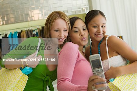 3 Girl friends Posing for Camera Phone Picture in clothing store