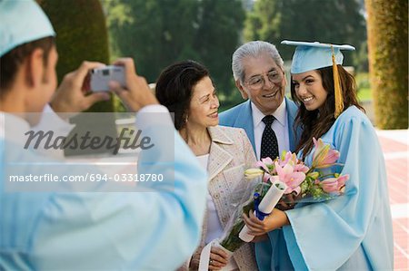 Graduate taking picture of other graduate and grandparents outside